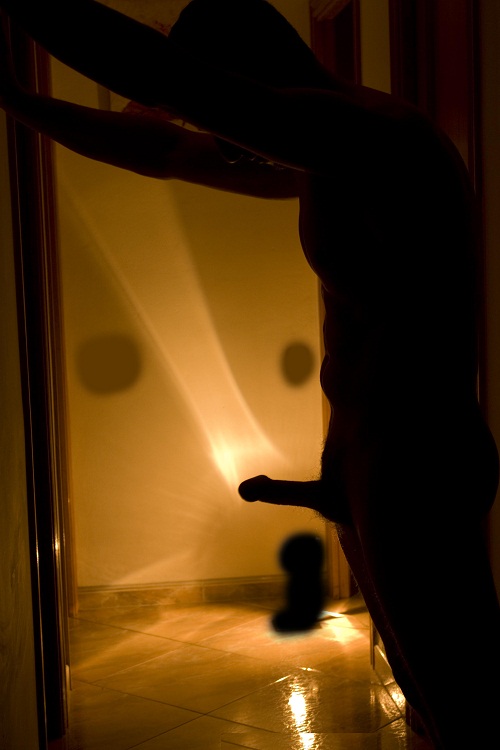 Hombre desnudo en la oscuridad con el pene erecto